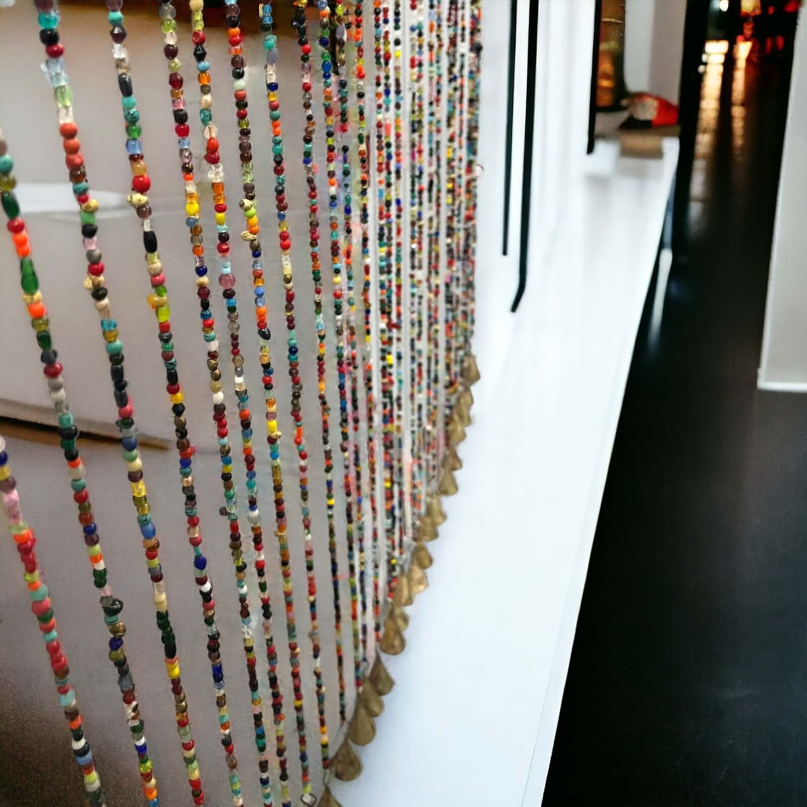 Colorful beaded curtain garland with jingle bells, perfect for doorway or room divider, handmade sustainable decor.